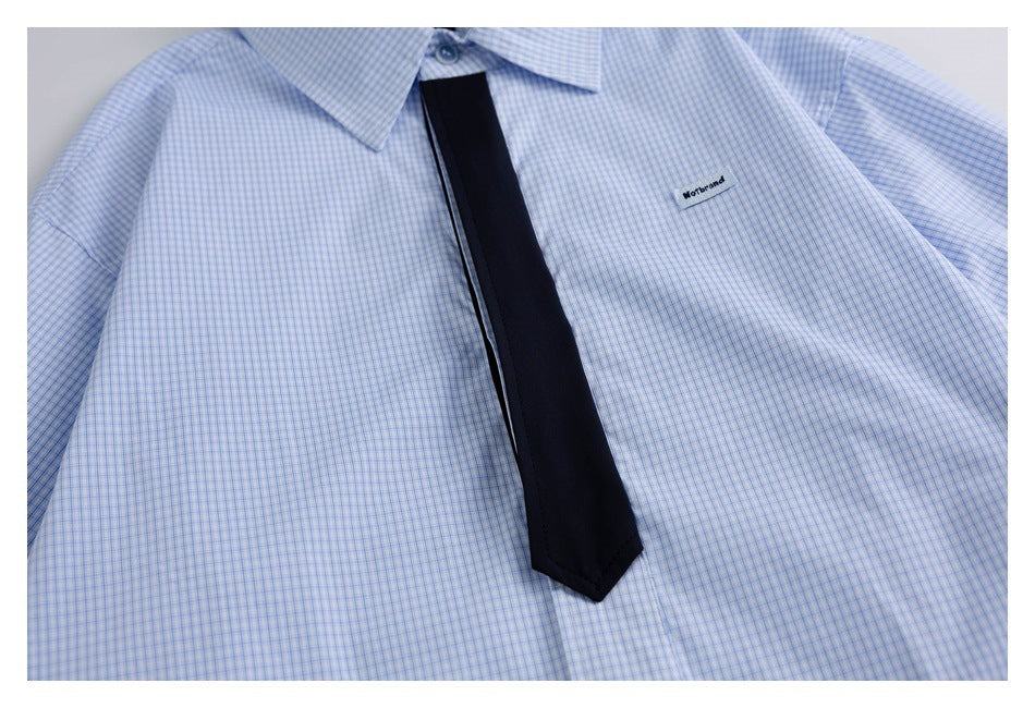 Front flat lay of a light blue fine-check button-up shirt with a black tie.