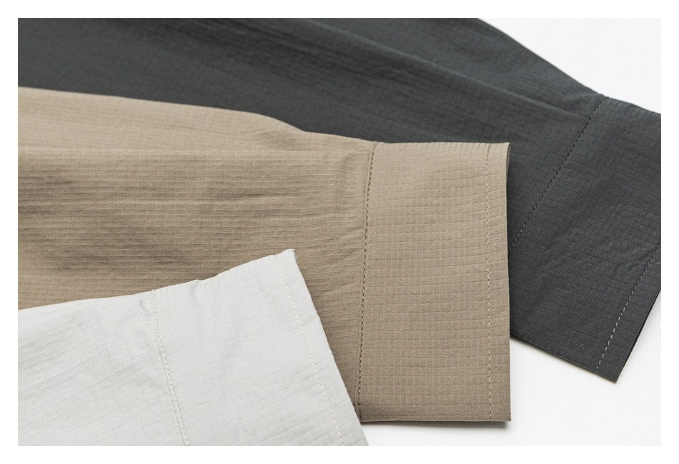 Close-up of white, taupe, and charcoal shirt sleeve cuffs showing their stitching and subtle grid texture.