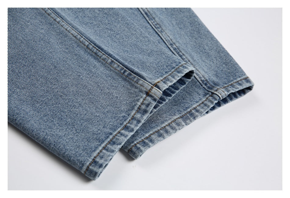Close-up of the hem of faded blue jeans, showing the folded edge and double stitching.
