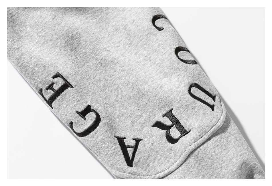 Close-up of black lettering on a light gray sweatshirt sleeve.