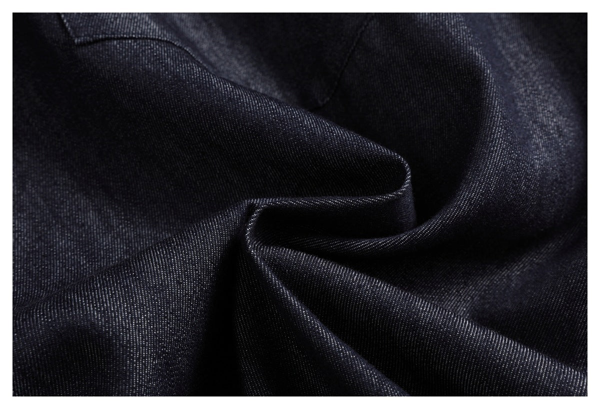 Close-up of dark indigo fabric arranged in folds, showing its diagonal weave texture.