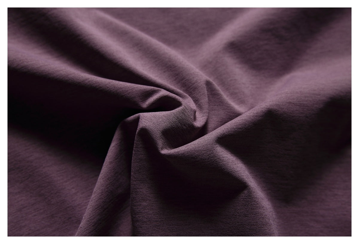 Close-up of dark plum-purple fabric draped into soft folds, showing a fine knit texture.