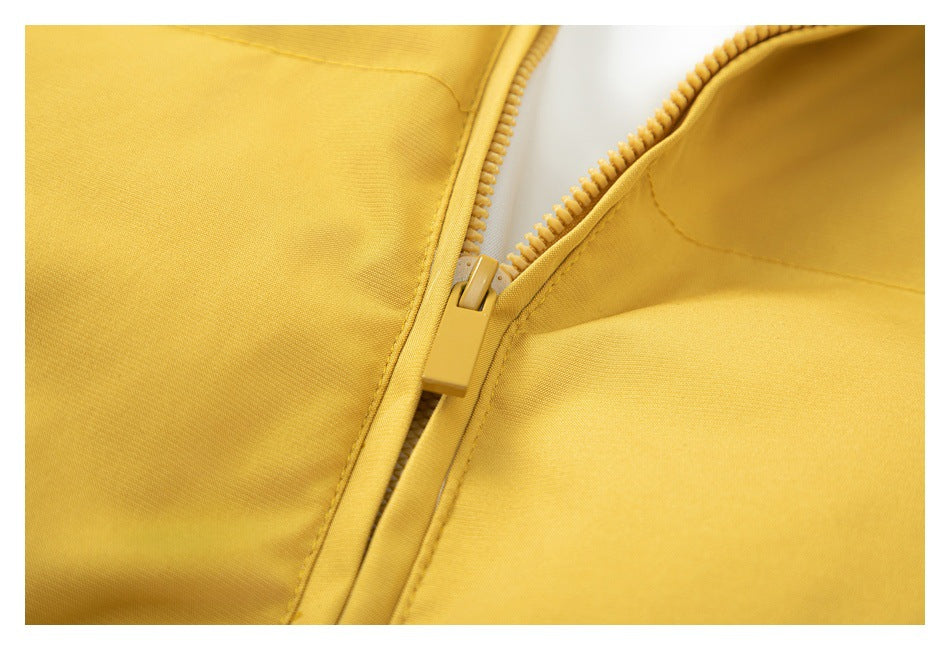 Close-up of a mustard-yellow garment's front zipper and stitching.