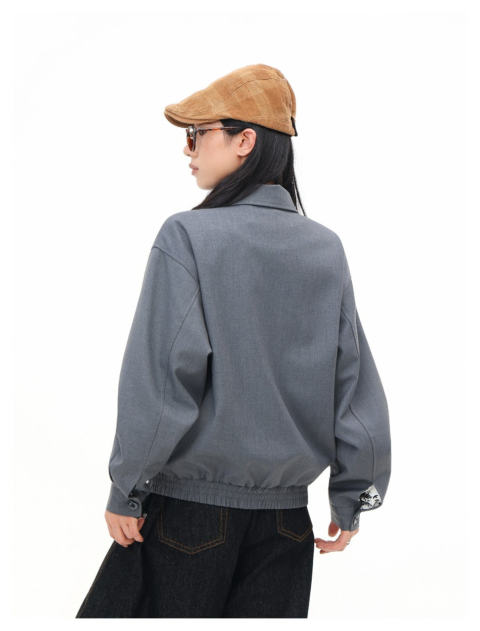 Model wearing the back of a gray zip-front jacket with an elastic hem and buttoned cuffs.
