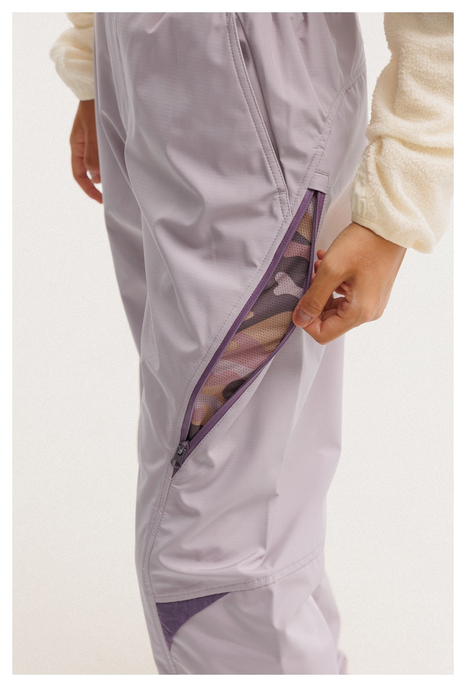 Close-up of a lavender trouser leg with a purple-trimmed zipper opening to reveal patterned mesh.