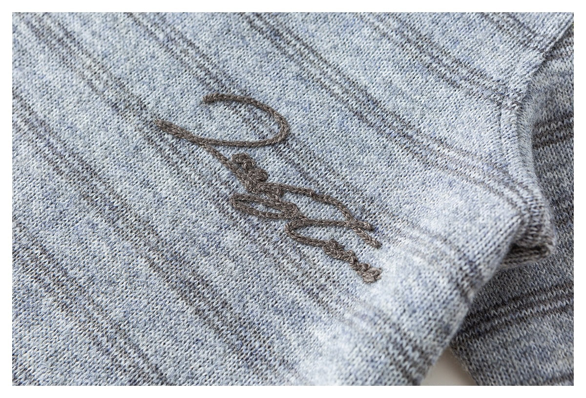 Dark script embroidery shown close-up on gray heathered knit fabric.