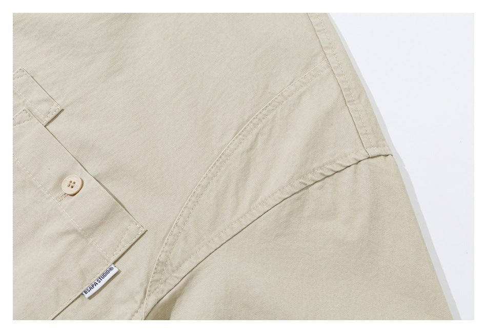 Close-up of beige garment fabric with a buttoned flap, curved seam, and small woven label.