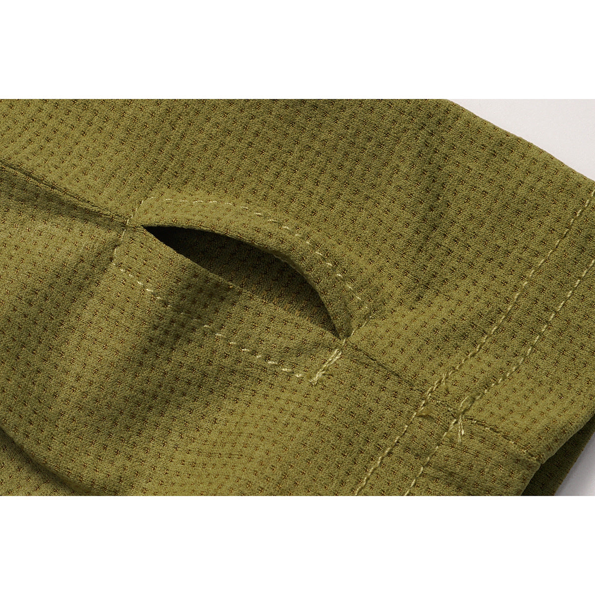 Close-up of an olive garment seam and curved opening against textured fabric.