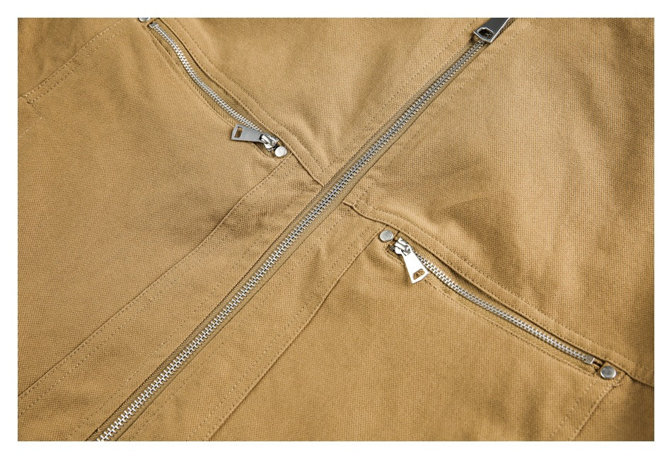 Close-up of a tan jacket front with a main zipper and two silver zippered pockets.