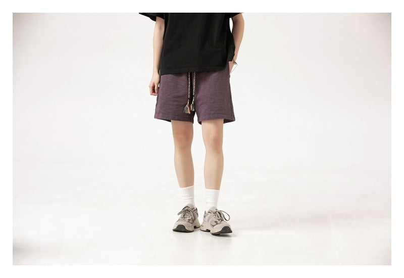 Front view of a model wearing muted purple drawstring shorts with a black T-shirt.