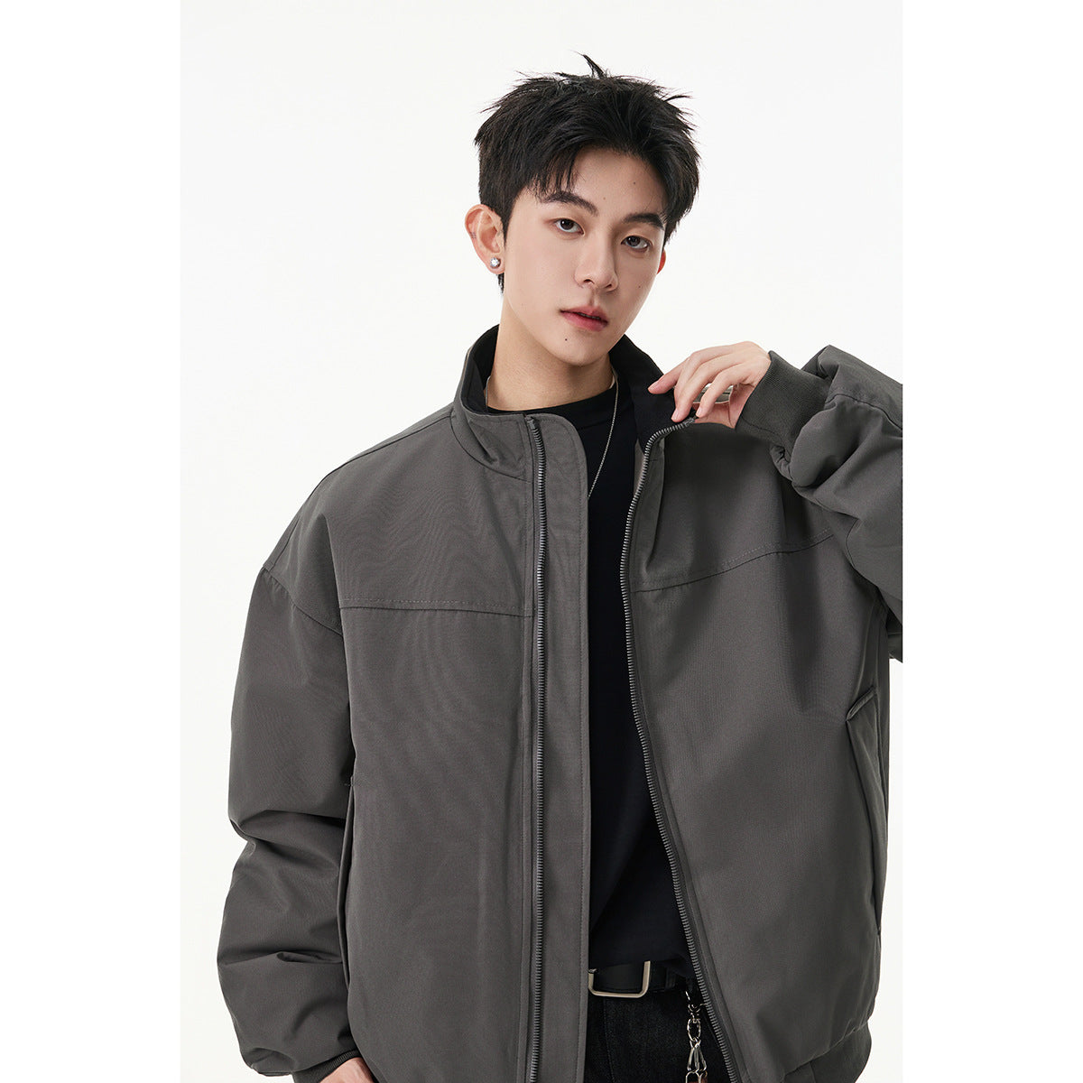 Model wearing a charcoal gray oversized zip-up jacket with a stand collar and front pockets.