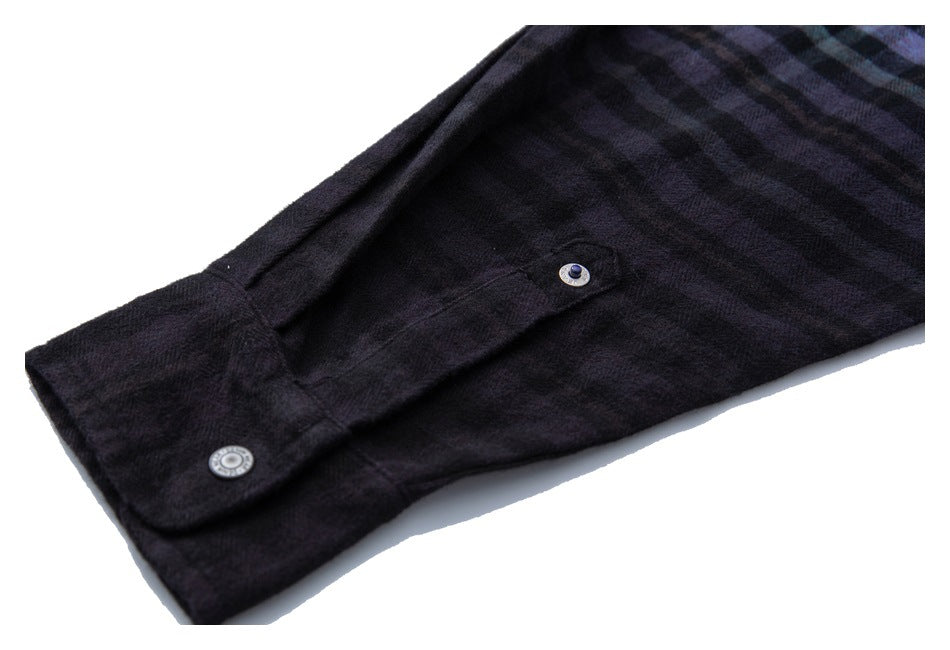 Close-up of a dark plaid shirt cuff with two round metal buttons.