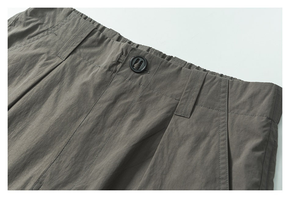 Close-up of gray shorts waistband with belt loops, stitching, and a black button.