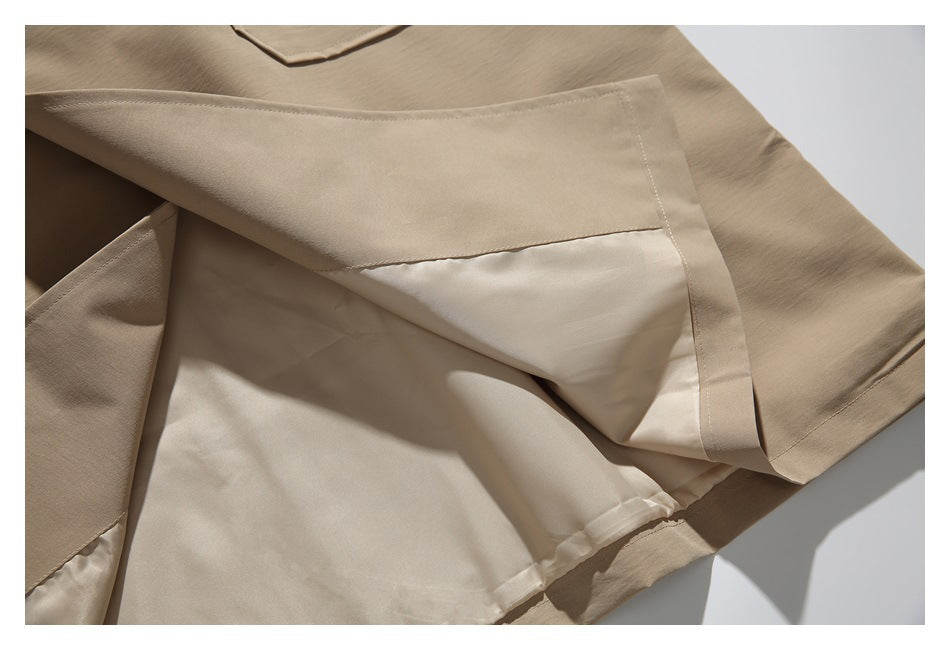 Close-up of the beige coat's pale inner lining, folded outer fabric, and hem stitching.