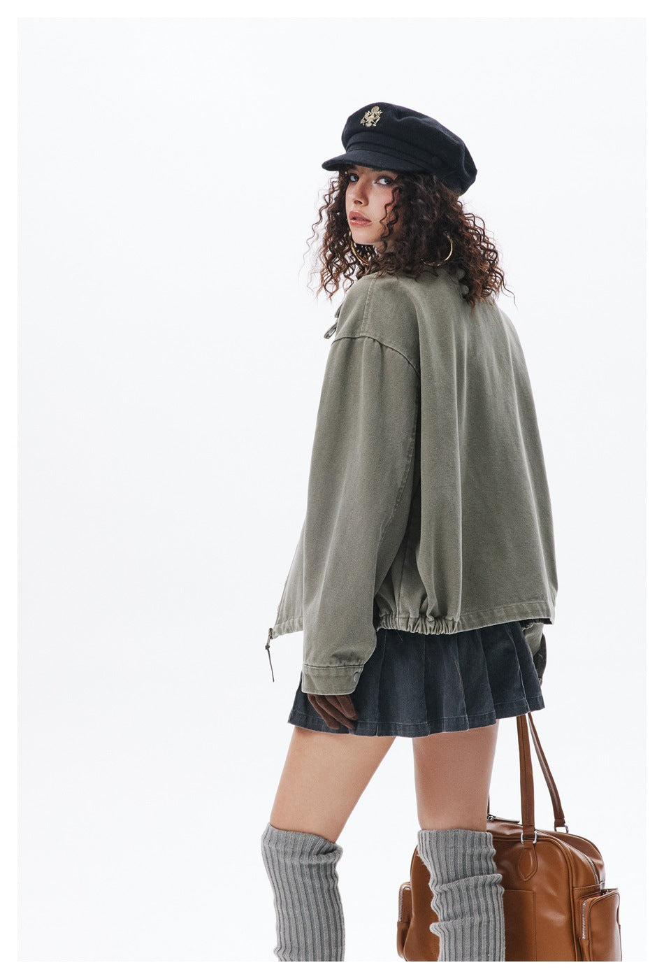 Back three-quarter view of model in green jacket showing drawcord gathered hem and buttoned cuff