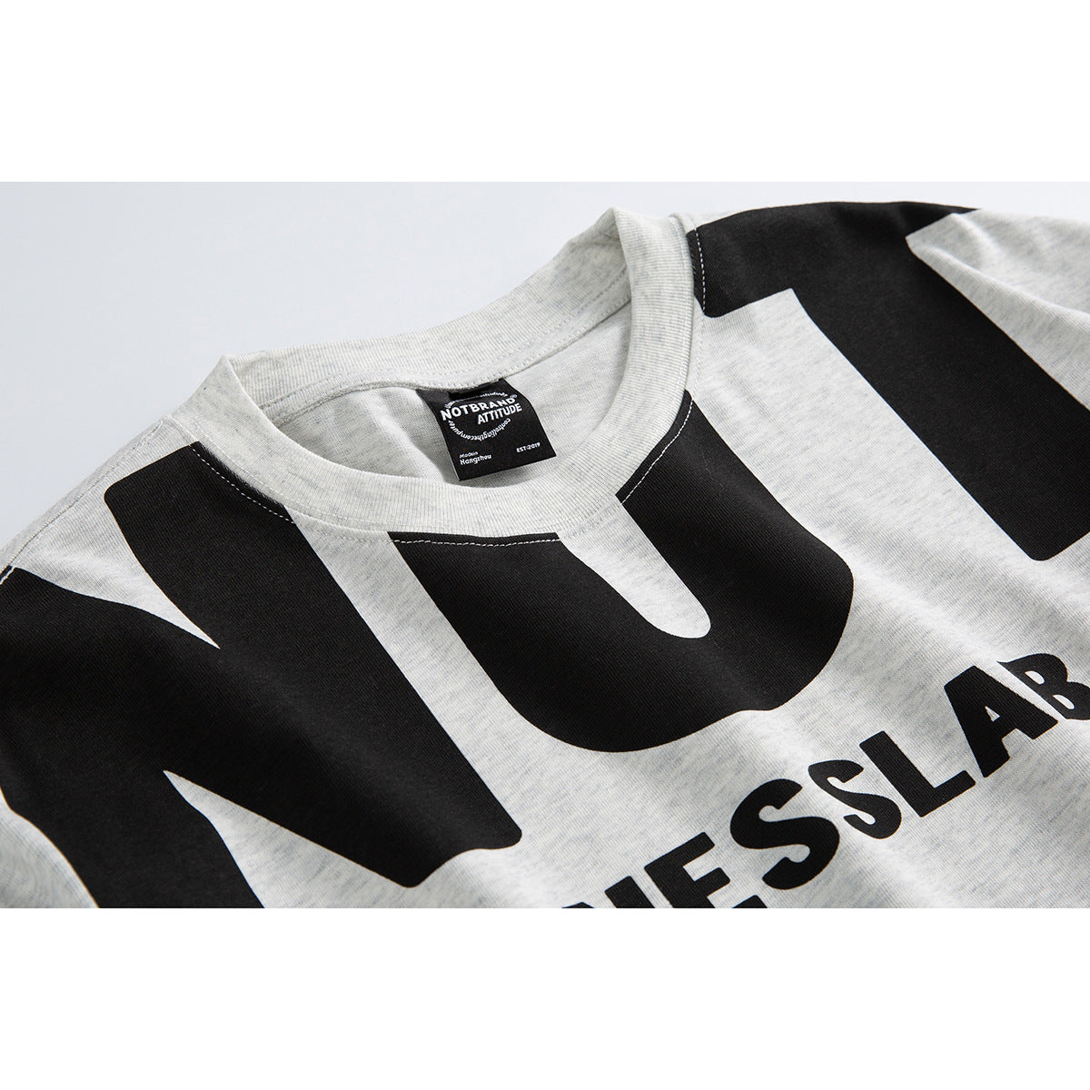 Close-up of a light gray T-shirt neckline and bold black graphic lettering.