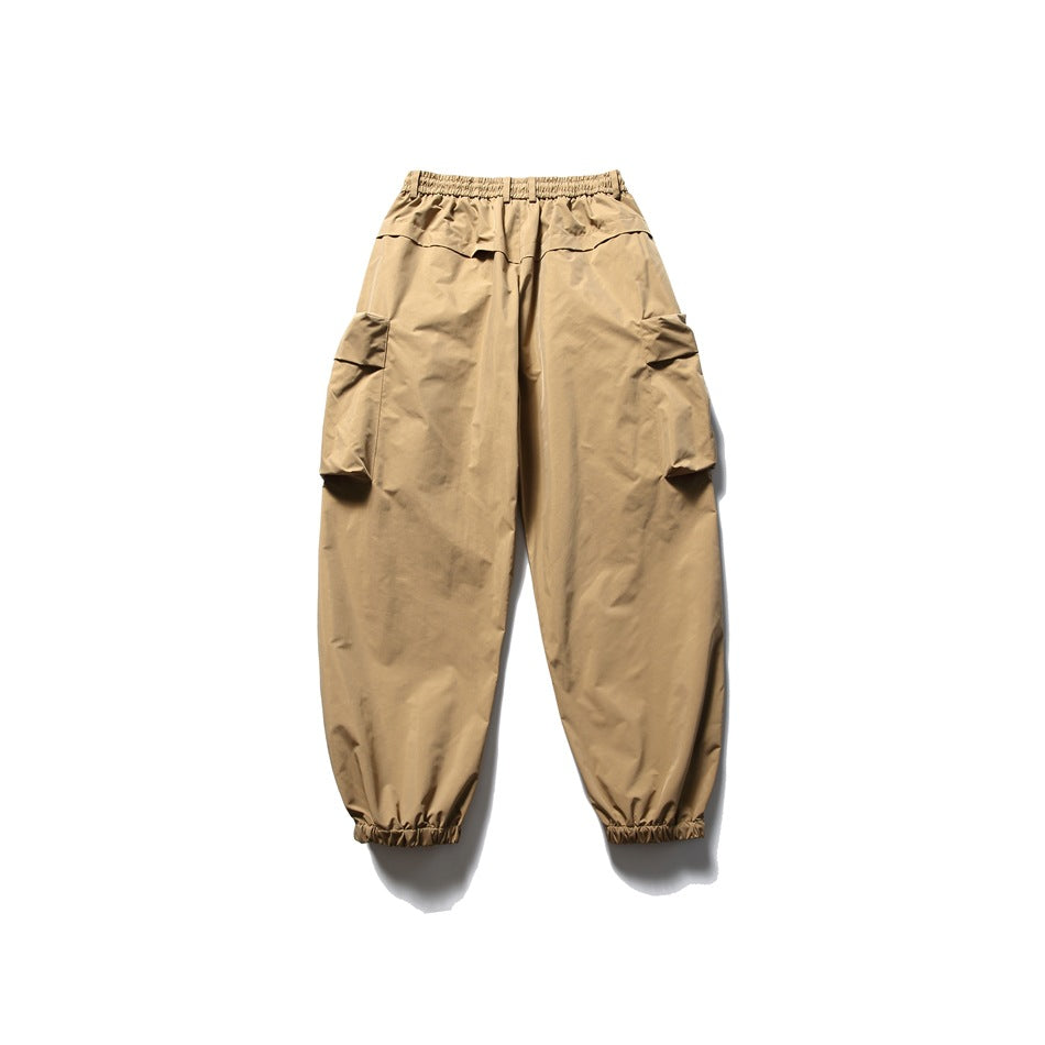 Front view of tan cargo pants with an elastic waistband, side cargo pockets, and gathered ankle cuffs.