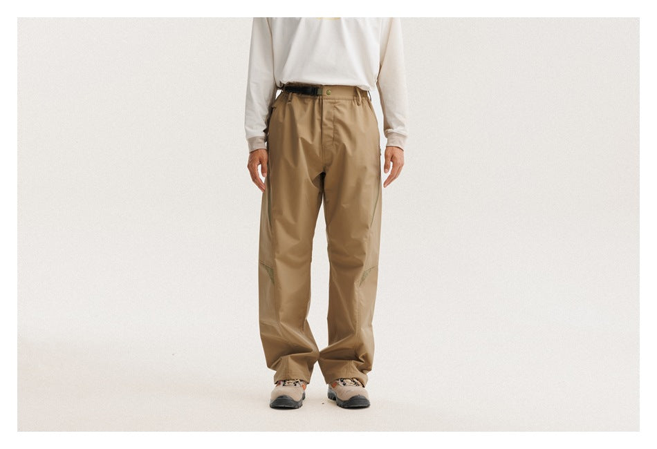Front view of a model wearing loose khaki trousers with an elastic waist and subtle green knee accents.