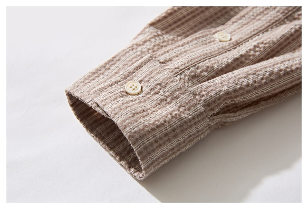 Close-up of a buttoned cuff on a beige-brown patterned shirt sleeve.