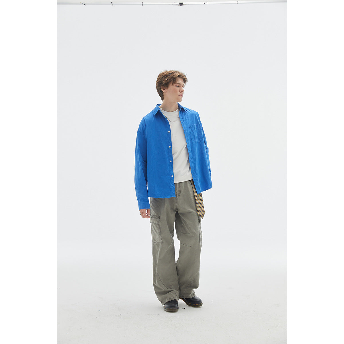 Model wearing a bright blue button-up shirt over a white tee with gray cargo pants.