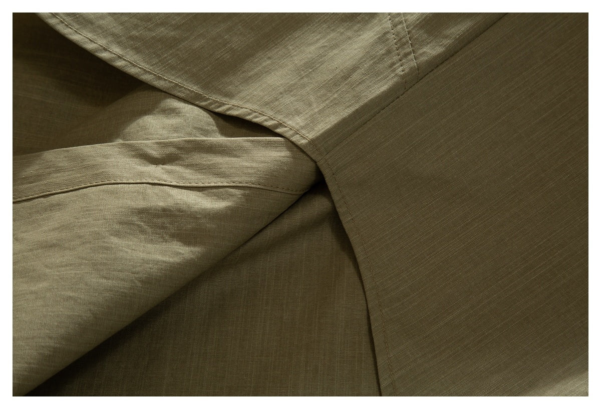 Close-up of overlapping olive-khaki shirt panels and stitched seams.