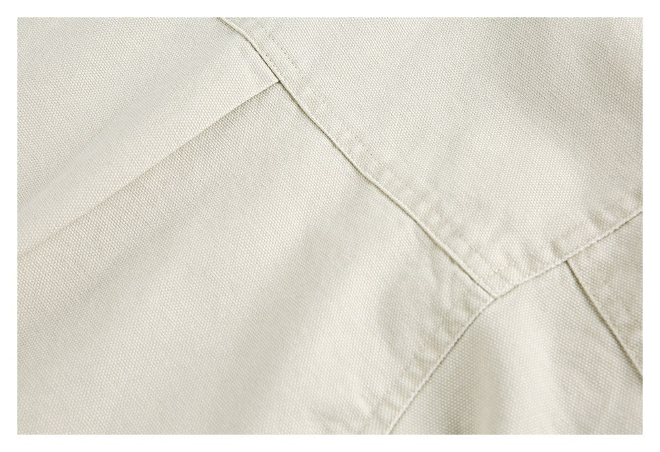Close-up of overlapping light beige garment panels with stitched seams.