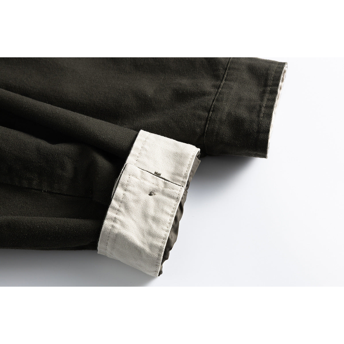 Close-up of the olive jacket's sleeve cuff, showing pale contrast lining folded back.