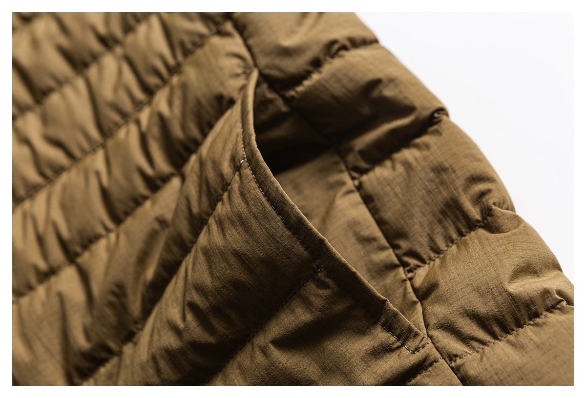 Close-up of a brown quilted jacket pocket opening and its stitched edge.