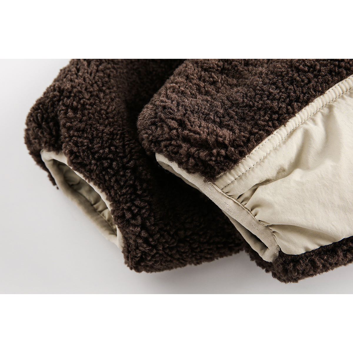 Close-up of dark brown sherpa jacket cuffs beside a cream quilted panel with visible stitching.