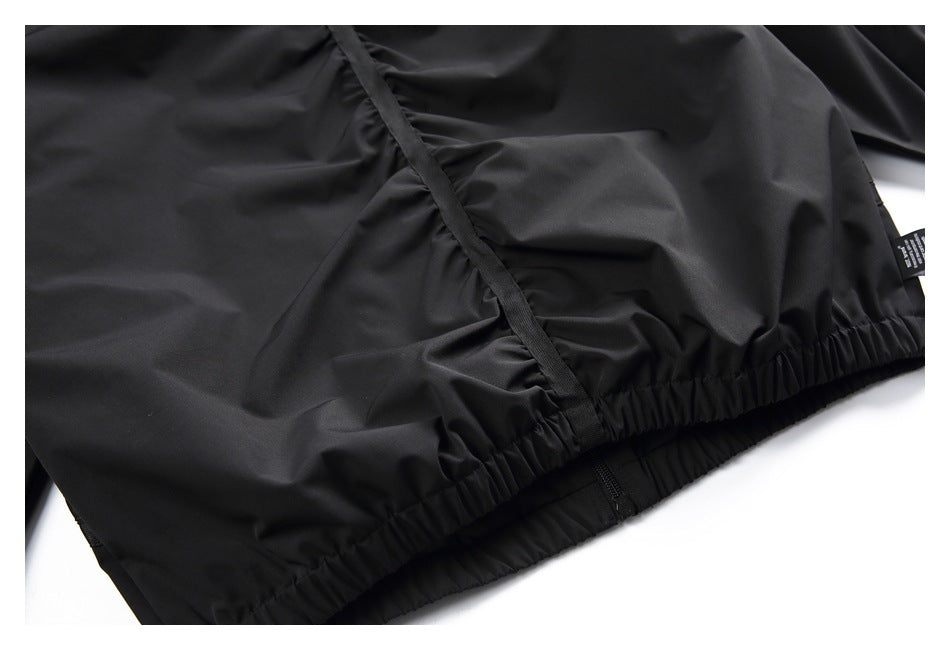 Close-up of a black garment’s gathered elastic edge, zipper, and small side tag.