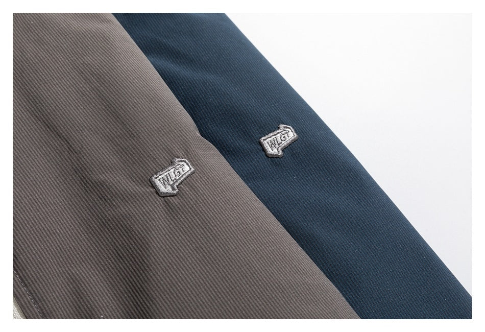 Close-up of embroidered emblems on gray and navy garment fabric.
