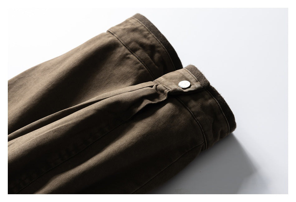 Close-up of a brown jacket sleeve cuff with a silver snap button and stitched seams.