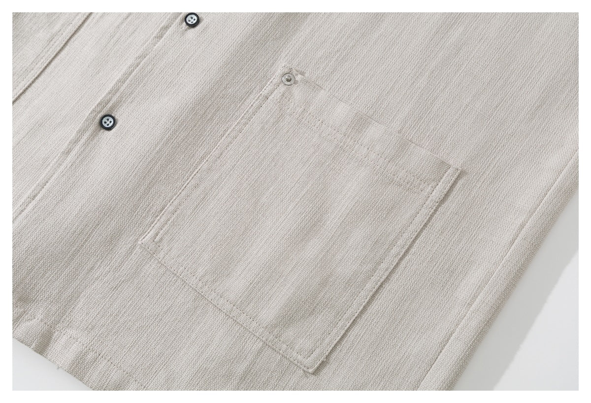 Close-up of a square chest pocket and buttons on the light beige shirt.