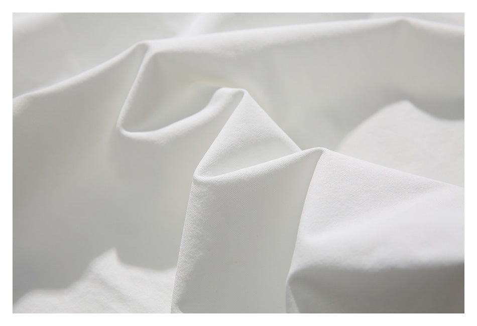 Close-up of softly folded white garment fabric showing its smooth surface and subtle texture.