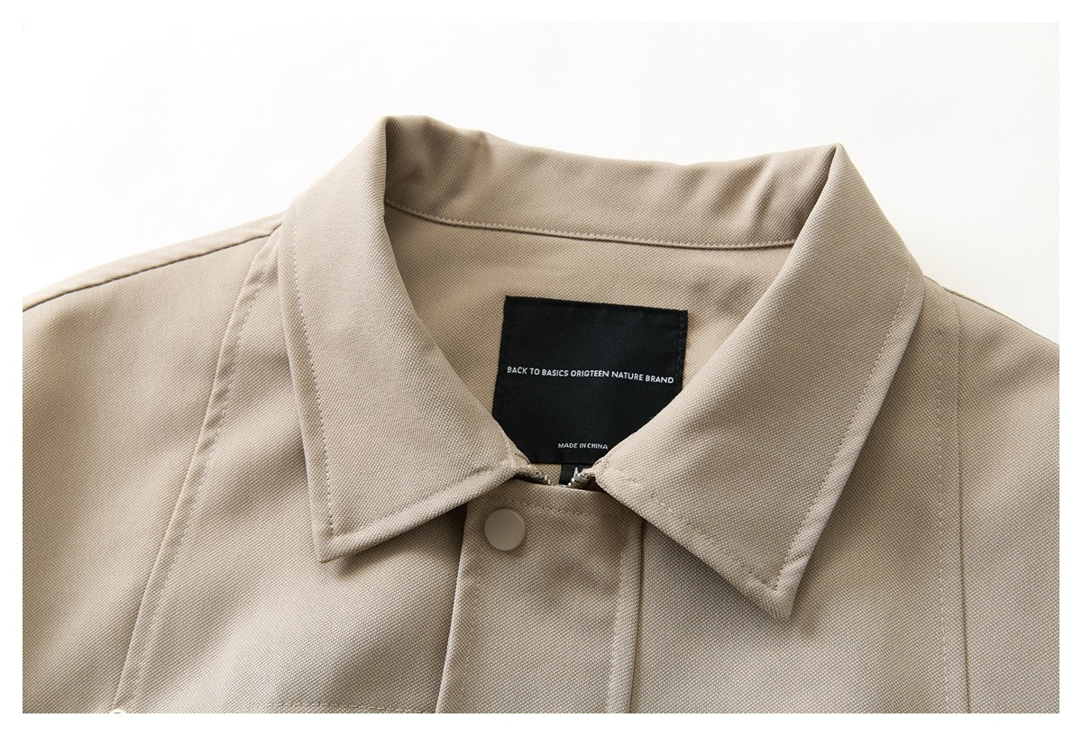 Close-up of a beige jacket collar, front snap, and black inner neck label.
