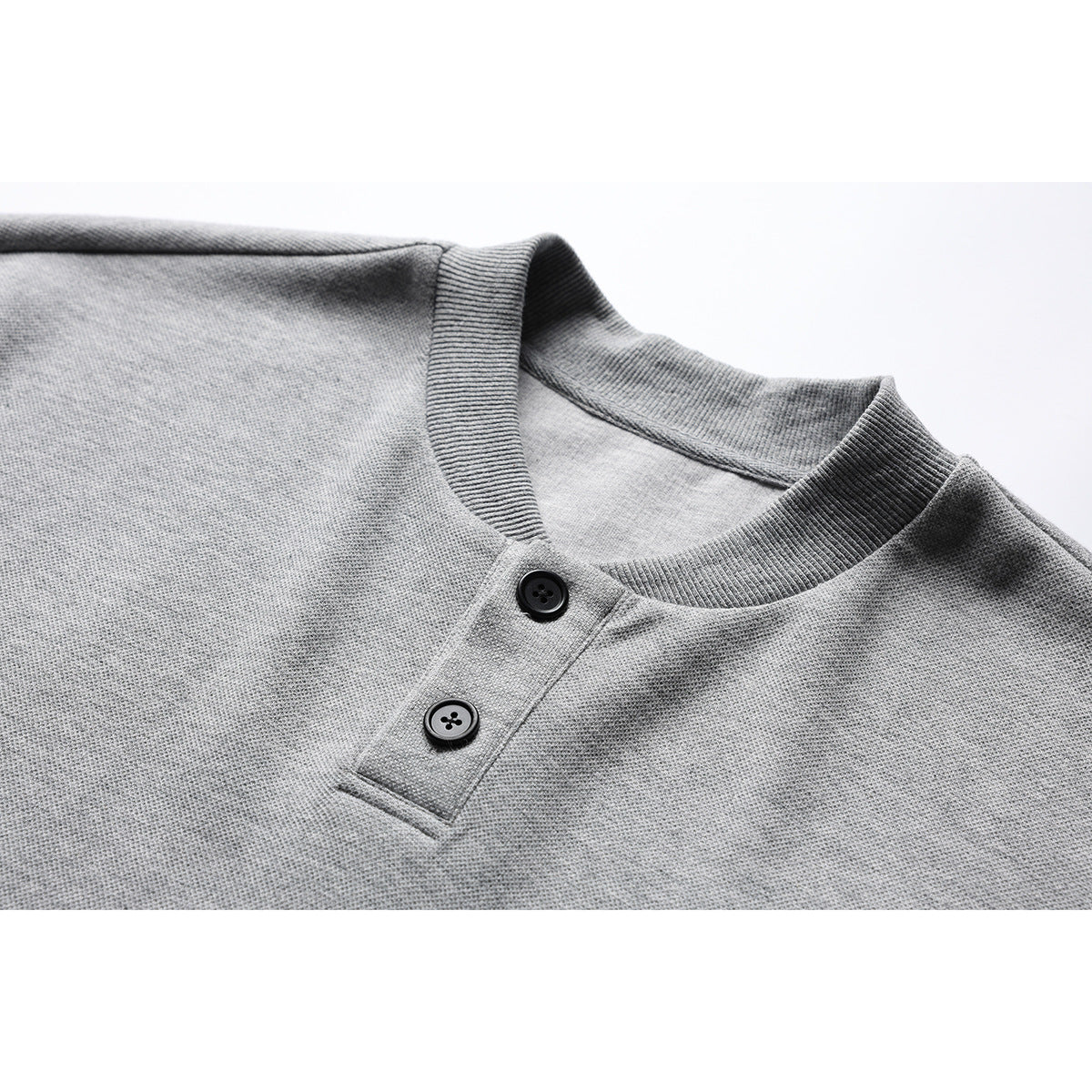 Close-up of a heather-gray shirt's ribbed crew neckline and two-button Henley placket.