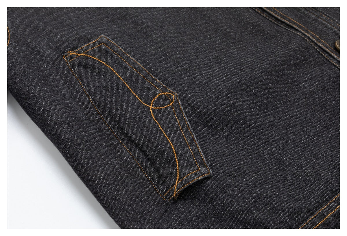 Close-up of a dark charcoal denim pocket with orange contrast stitching.