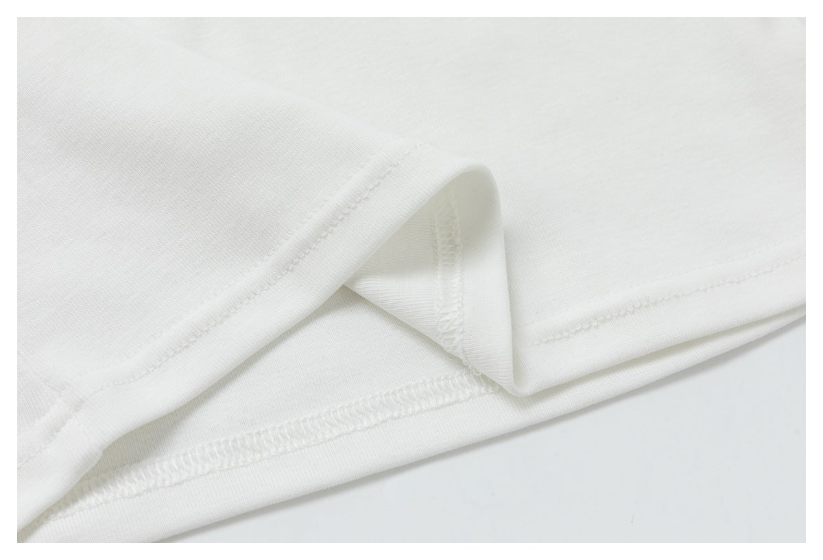 Close-up of a white garment hem with visible stitching and folded fabric.