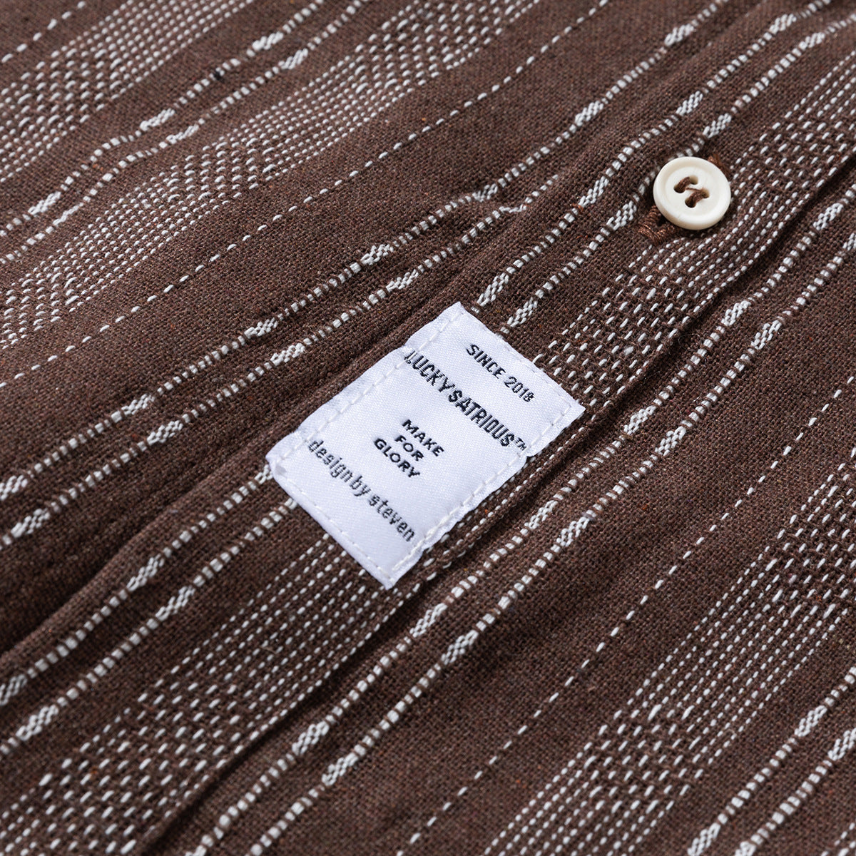 Close-up of a brown striped shirt fabric and its sewn-in white label.