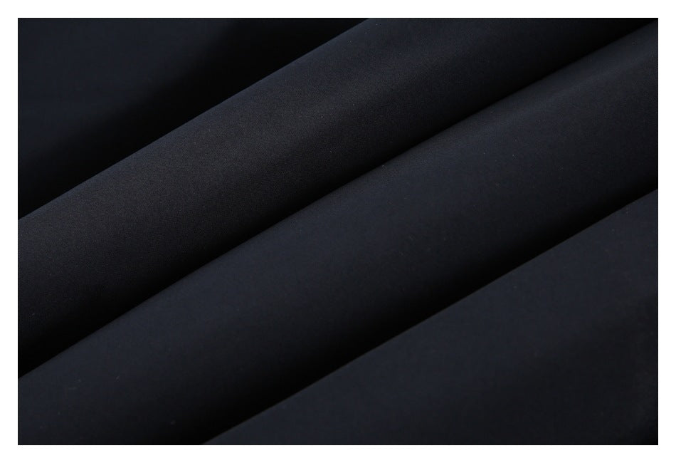 Close-up of smooth black fabric arranged in broad folds.