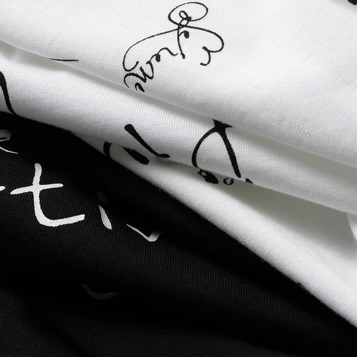 Close-up of folded white and black T-shirts with contrasting handwritten-style prints.