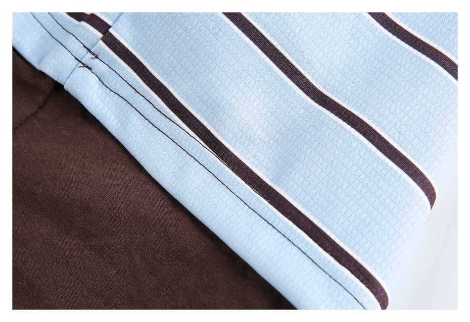 Close-up of a stitched edge on light blue fabric with dark stripes, layered over brown fabric.