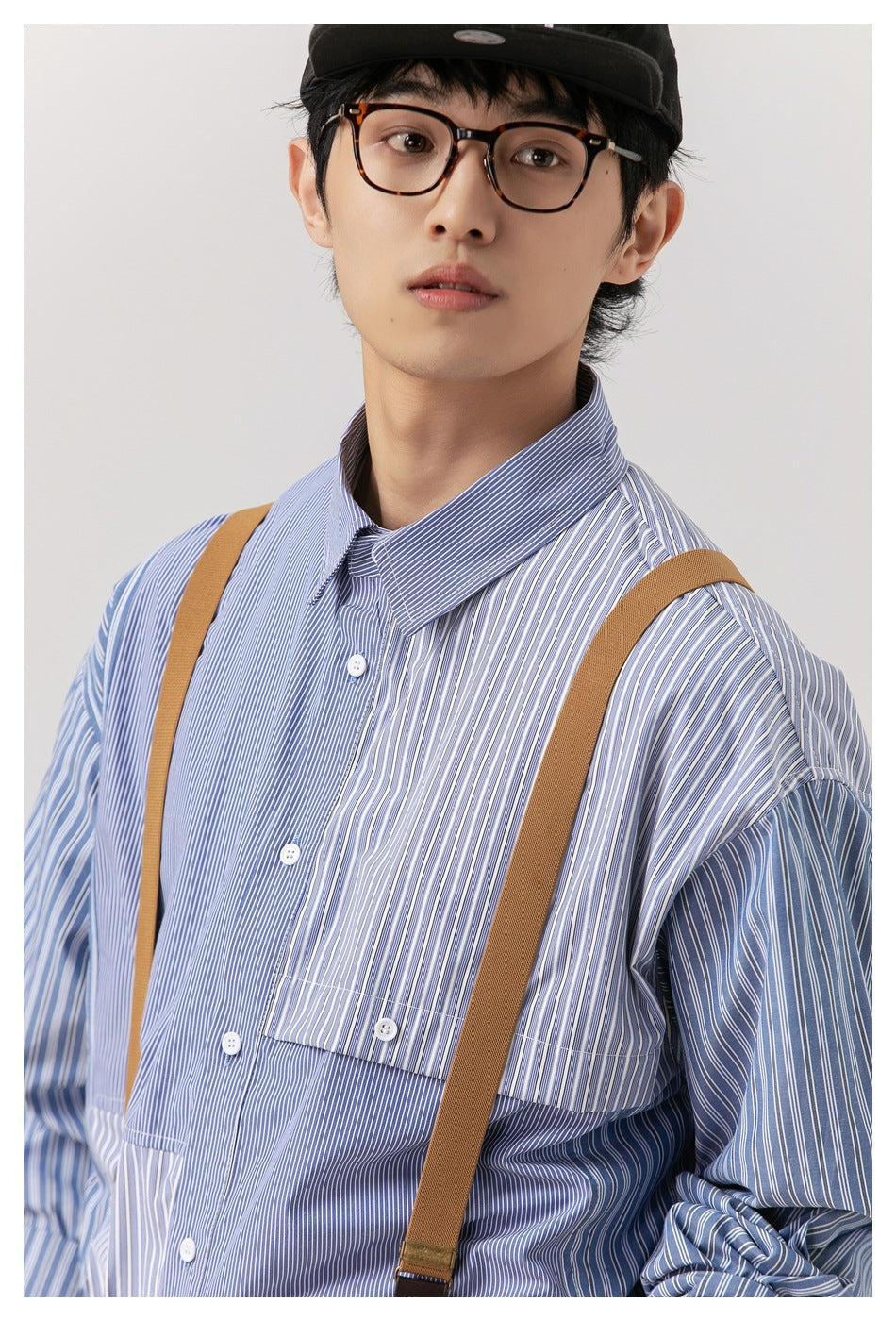 Close view of a model wearing a blue-and-white striped shirt with mixed stripe directions and a buttoned chest pocket.