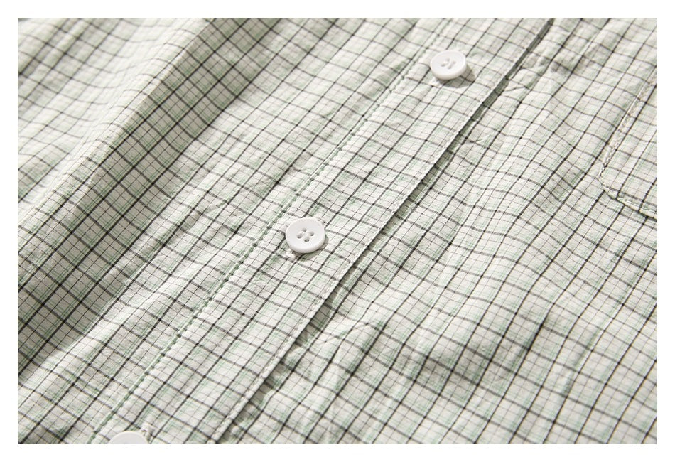 Close-up of the front placket and white buttons on a pale green and white plaid shirt.