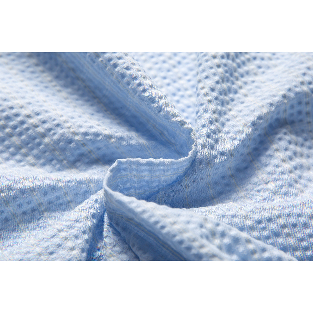 Close-up of the light blue shirt's raised woven texture and folded fabric edge.