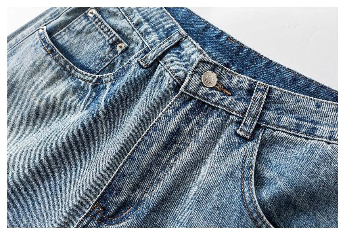 Cropped view of blue faded jeans showing the front waistband, button, belt loop and pockets.