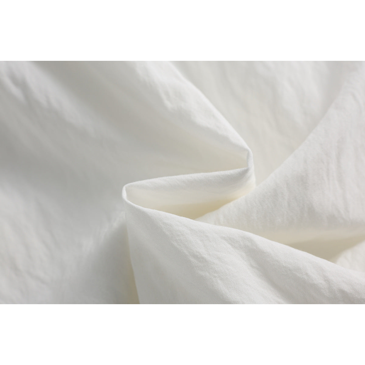 Close-up of white pant fabric folded to show its surface and drape.