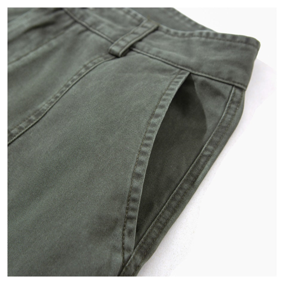 Close-up of an angled pocket opening and belt loop on olive-gray trousers.