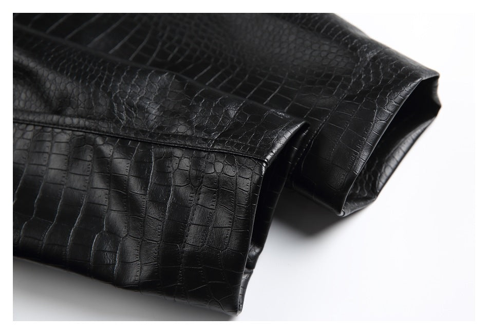 Close-up of glossy black crocodile-embossed garment panels folded over one another.