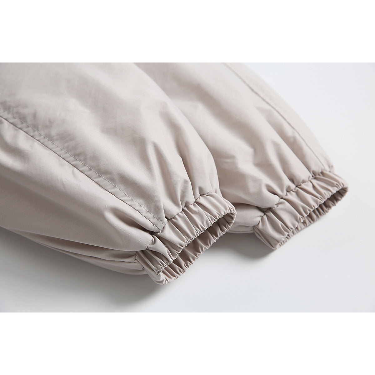 Close-up of a light beige jacket's gathered elastic cuffs and stitched sleeve seams.